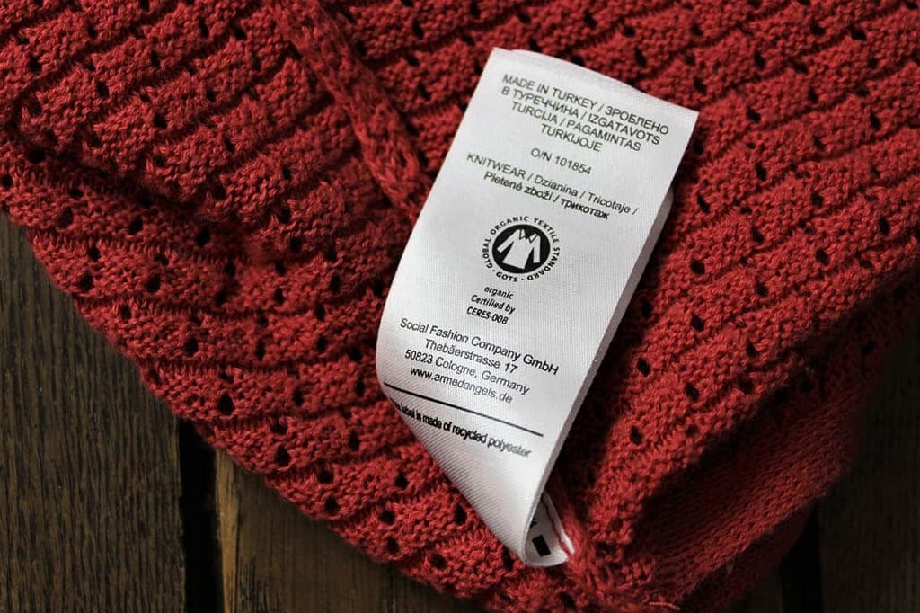 Zertifizierte Baumwolle mit Siegel und Etikett an rotem Pullover