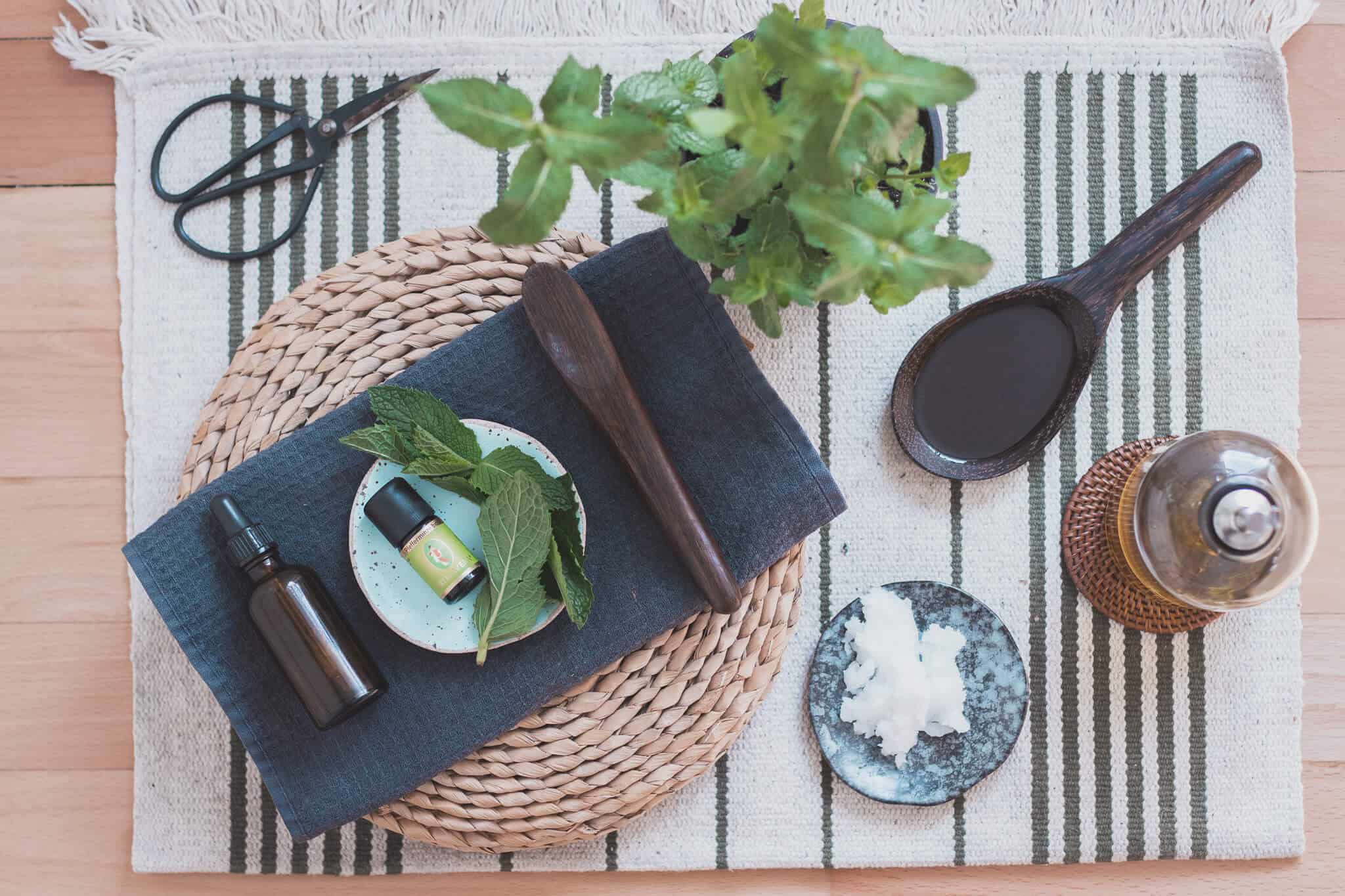 Kokosöl Olivenöl und Pfefferminzöl mit Minze und Schere auf Holzboden