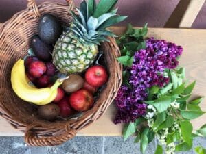 Bio Obst, Banane, Ananas und Äpfel in einem geflochtenen Korb