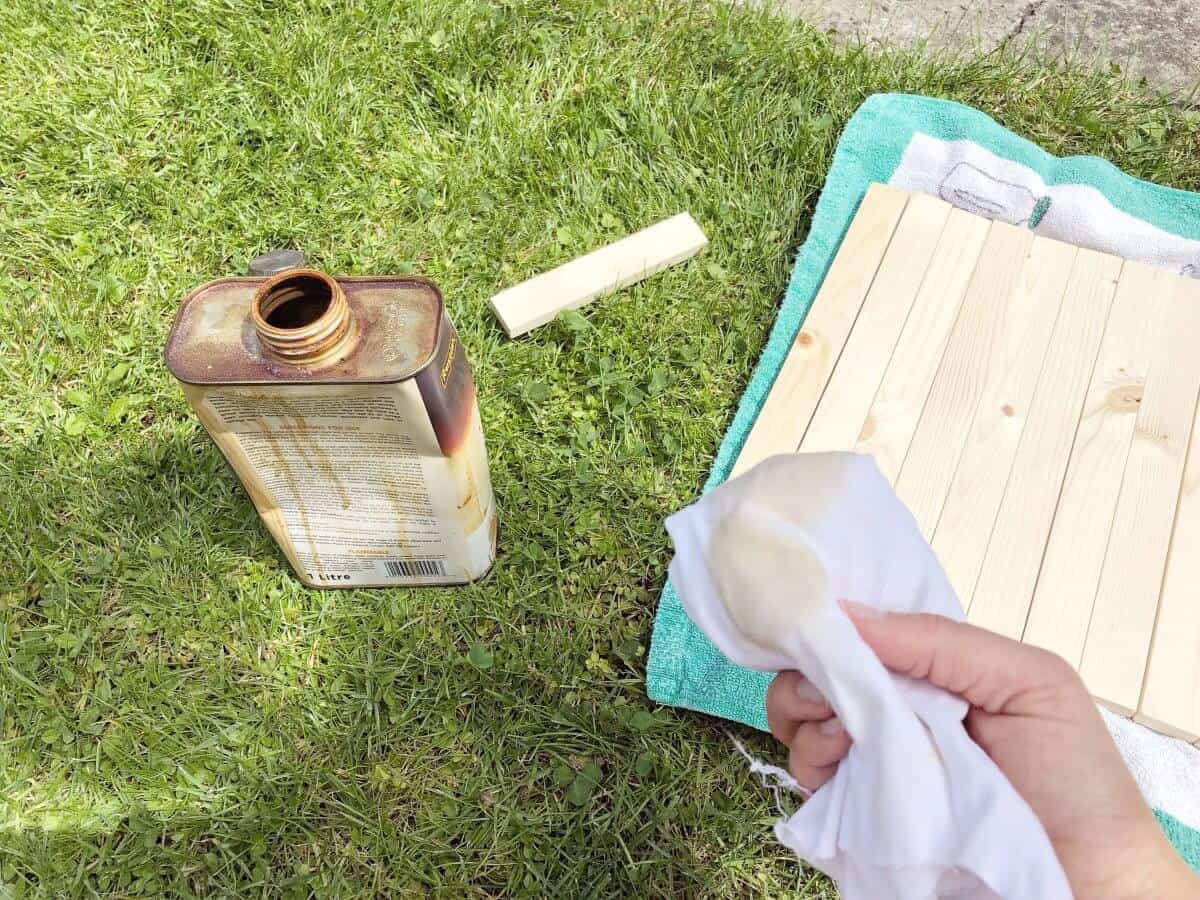 Dänisches Öl und Holz auf Rasen alter Lappen in der Hand