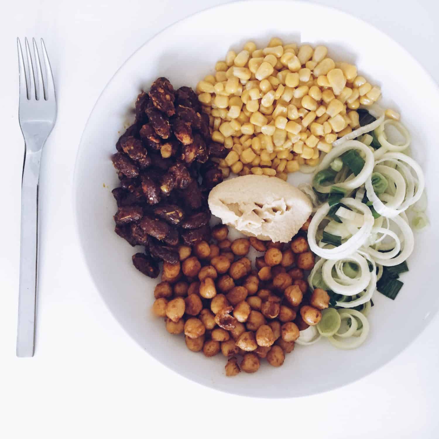 Hülsenfrüchte Mais Kichererbsen und Bohnen auf Teller mit Lauch und Hummus