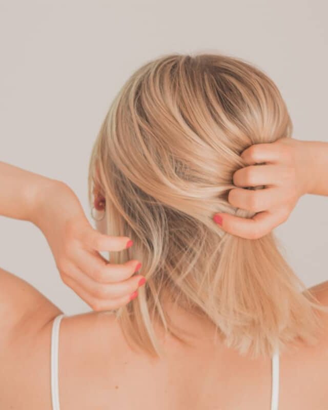 Blonde Frau fasst sich in Haare