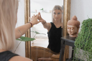 Frau schaut lächelnd in Spiegelbild und berührt mit Finger das Spiegelbild