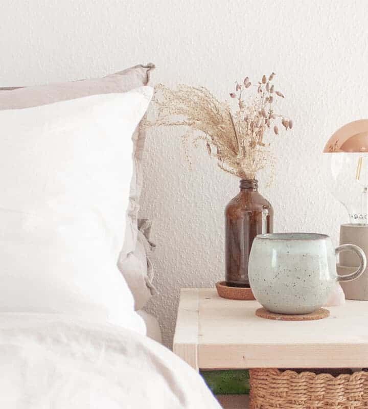 Weiße Bettwäsche und Nachttisch natürliches Holz Tasse auf Nachttisch