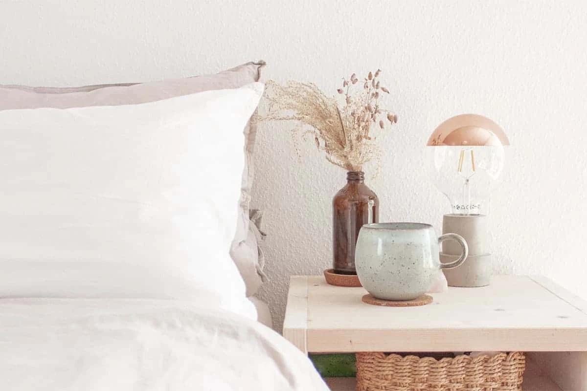 Weiße Bettwäsche und Nachttisch natürliches Holz Tasse auf Nachttisch