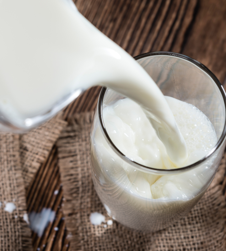 Milch aus Milchkanne wird in Glas eingeschänkt