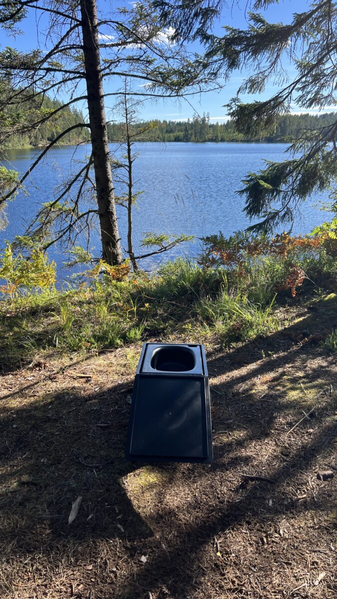 Die BOXIO Toilette, platziert an einem wunderschönen See Mitten im Wald.
